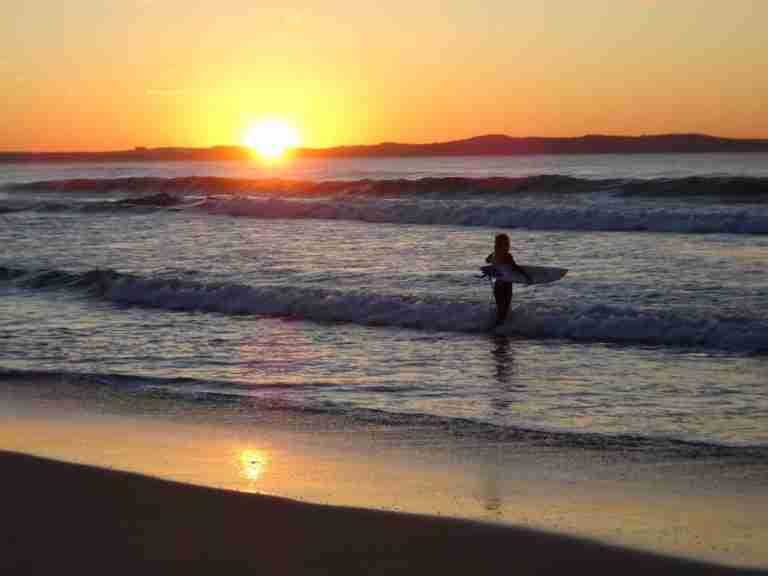 a surfer enjoying a Sydney sunrise at Cronulla Beach,one of the best Sydney day trips