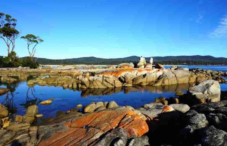 A stunning 14 day tasmania itinerary visiting the beautiful Bay of Fires orange lichen covered rocks, blue water and open skies