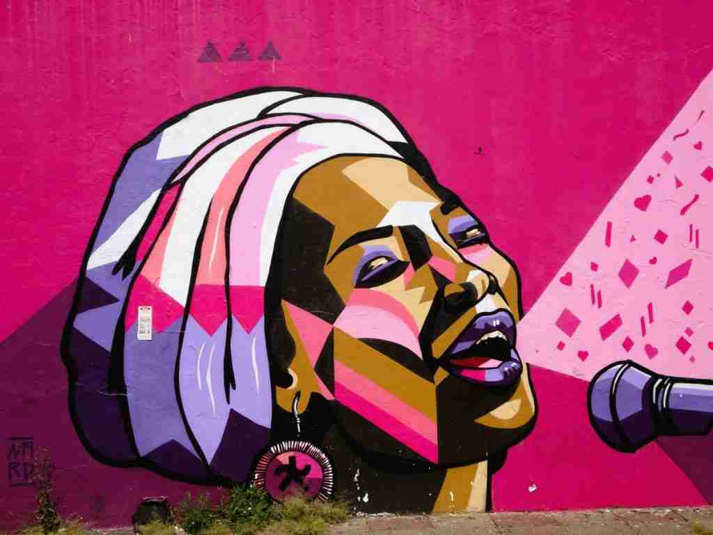 a colourful streetart painting of a black woman singing into a microphone in Johannesburg