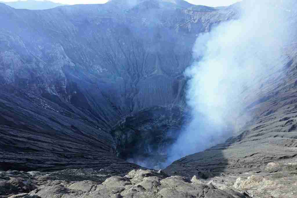 Standing at the edge of the Mount Bromo volcano near a plume of steam and gas