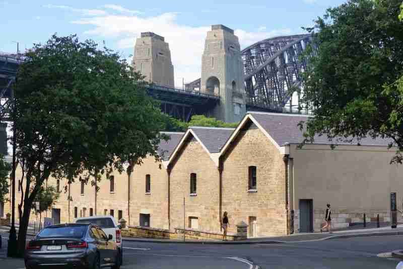 On a walking tour of The Rocks the Sydney Harbour Bridge appears behind heritage buildings 