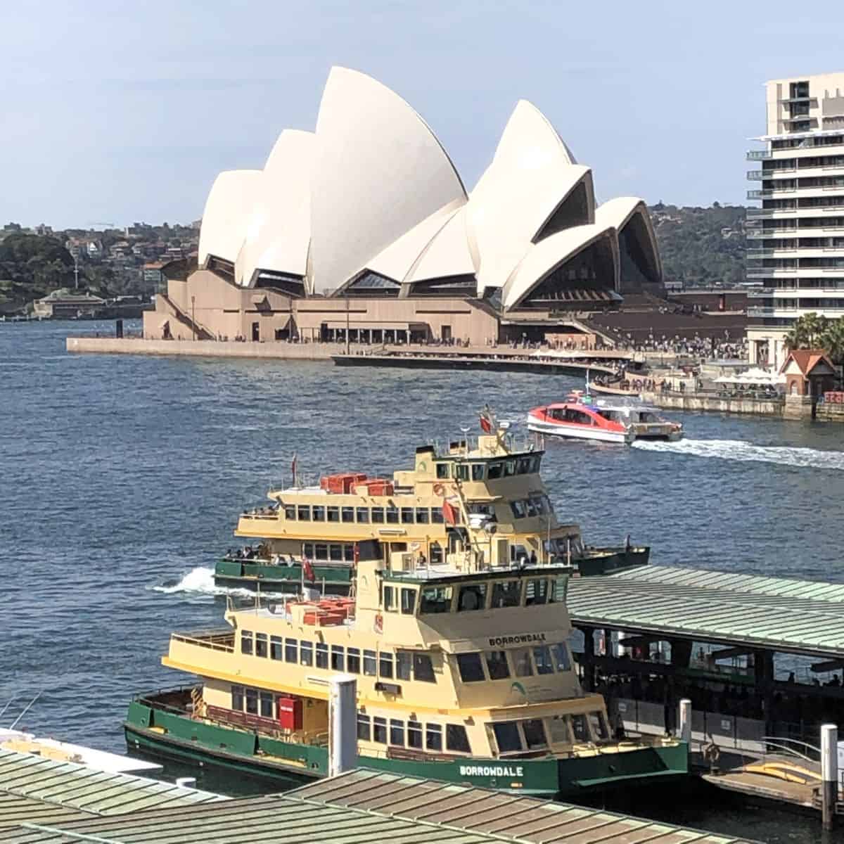 A green Sydney ferry with the Opera House behind