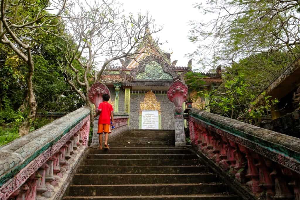a young boy climbing the stairs to a temple in Cambodia