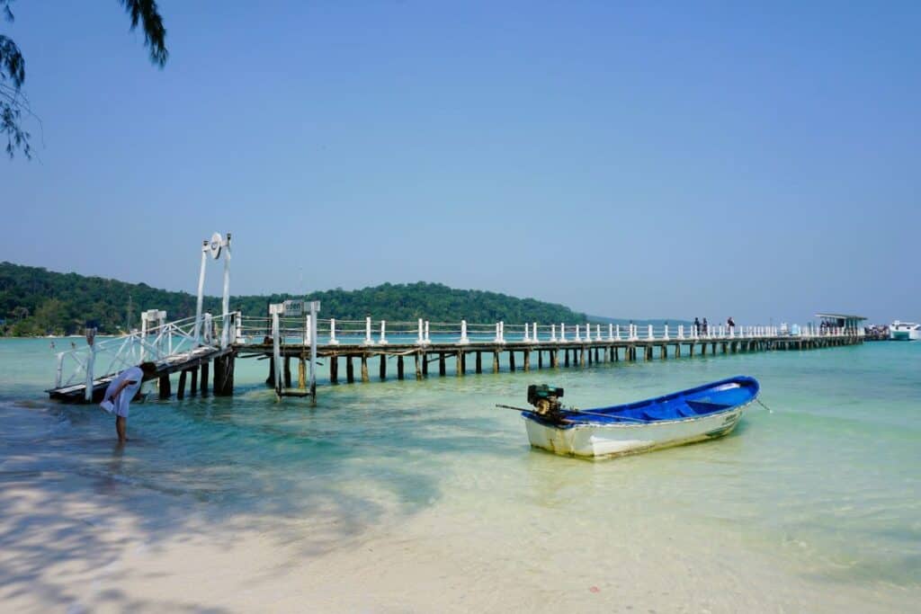 A small boat floating near a white pier in calm turquoise water