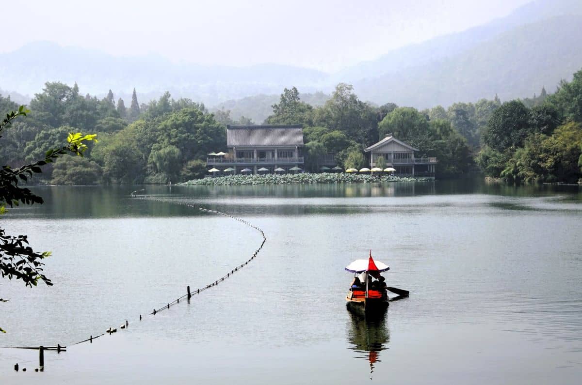 rowing baot on still lake with green hills and mountains behind