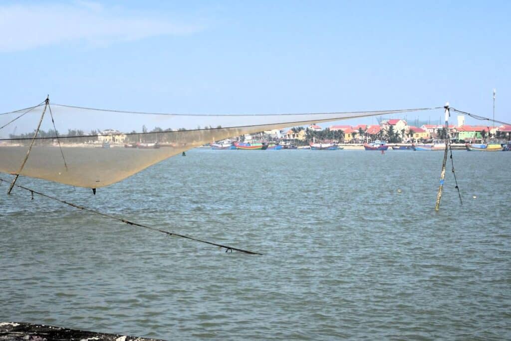 fishing nets on the coast with colourful houses in the distance