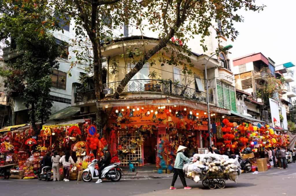Colourful stalls and a woman with a barrow in the Hanoi Old Quarter