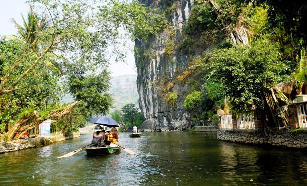Row boat on a river beneath tall limestone cliffs
