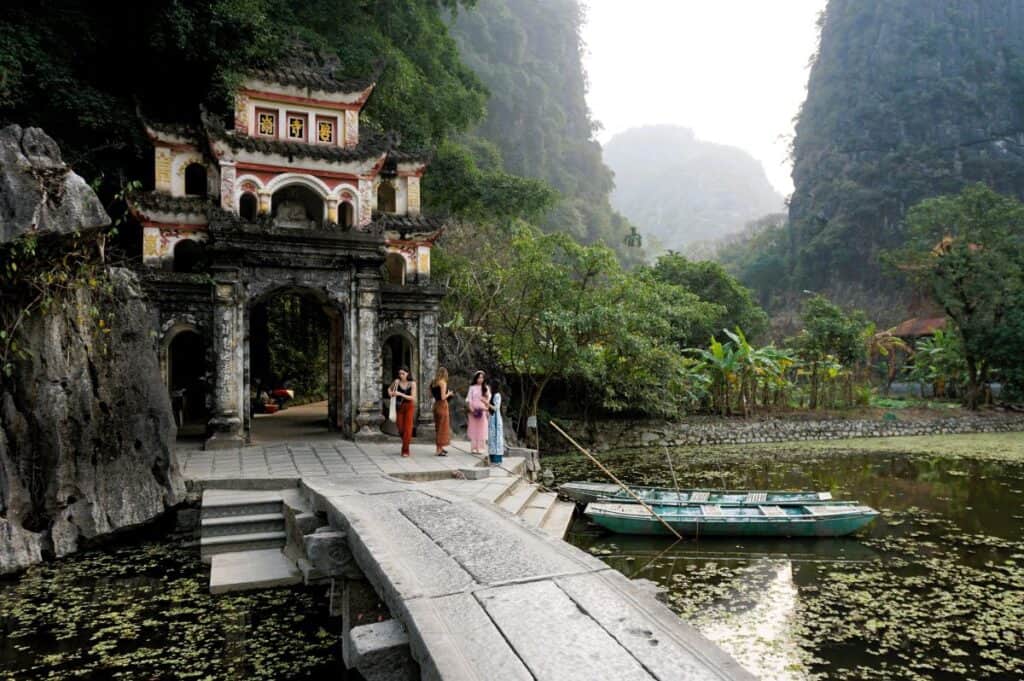stone bridge over a lake leading to a Vietnamese temple