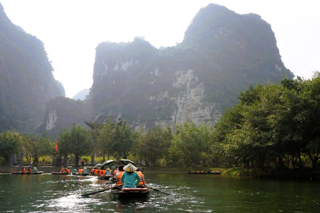 Rowboats on the river in Trang An Vietnam surrounded by green forests and tall mountains
