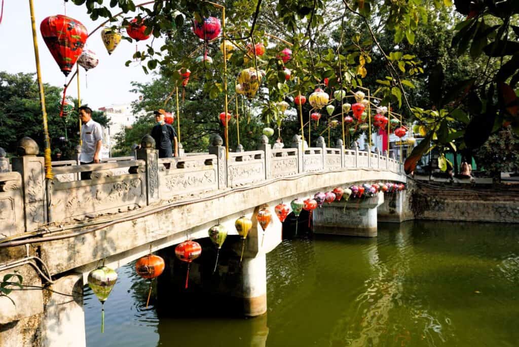 stone bridge over a river decorated with colourful lanterns in the Hoa Lu Old Town in Ninh Binh