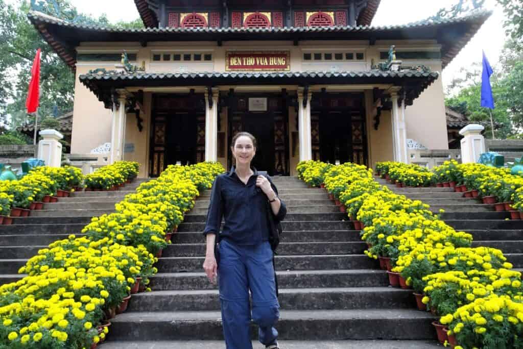 woman standing on the staits surrpunded by yellow flowers at the National History Museum on a South Vietnam itinerary