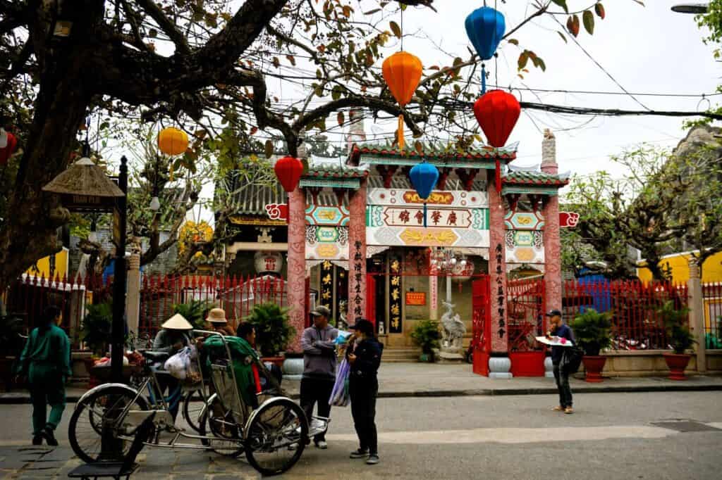Entrance to the Chinese Assembly hall in Hoi An with a cyclo and colourful lanterns decorating tree in front