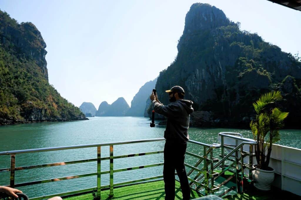a man on a cruise boat filming the stunning scenery on Lan Ha Bay Vietnam