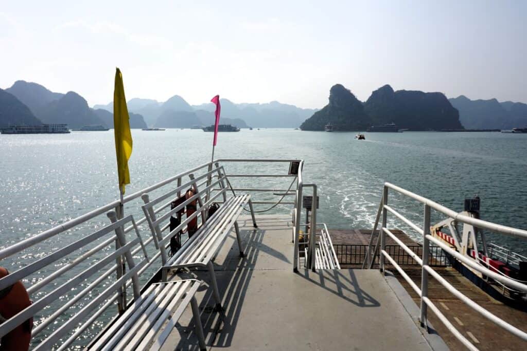 white railing and coloutful flags on the public ferrry in Halong Bay Vietnam
