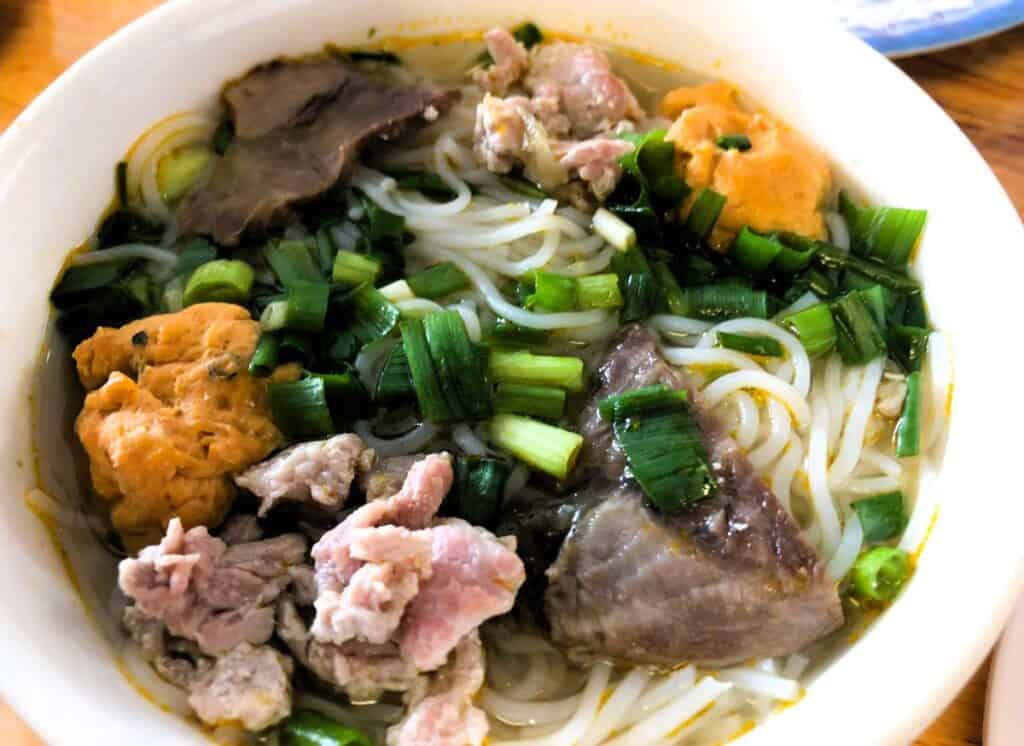 Bowl with soup, green veges, prok and rice noodles