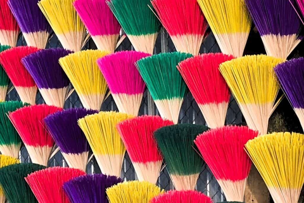 a wall with a dislpay of brightly coloured  insence sticks