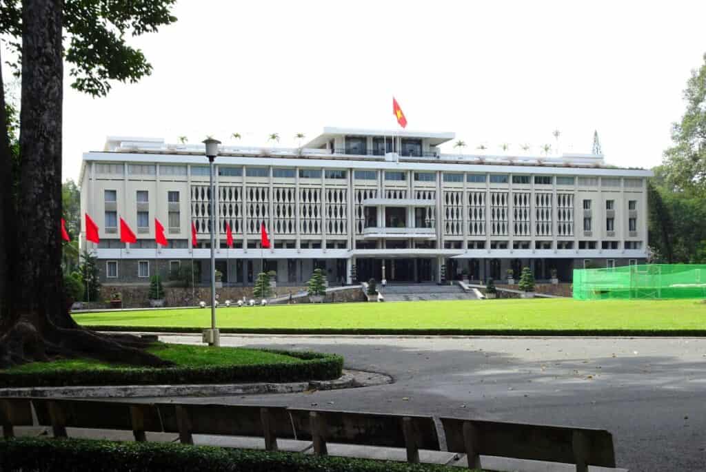 a white building with red flags and a green lawn